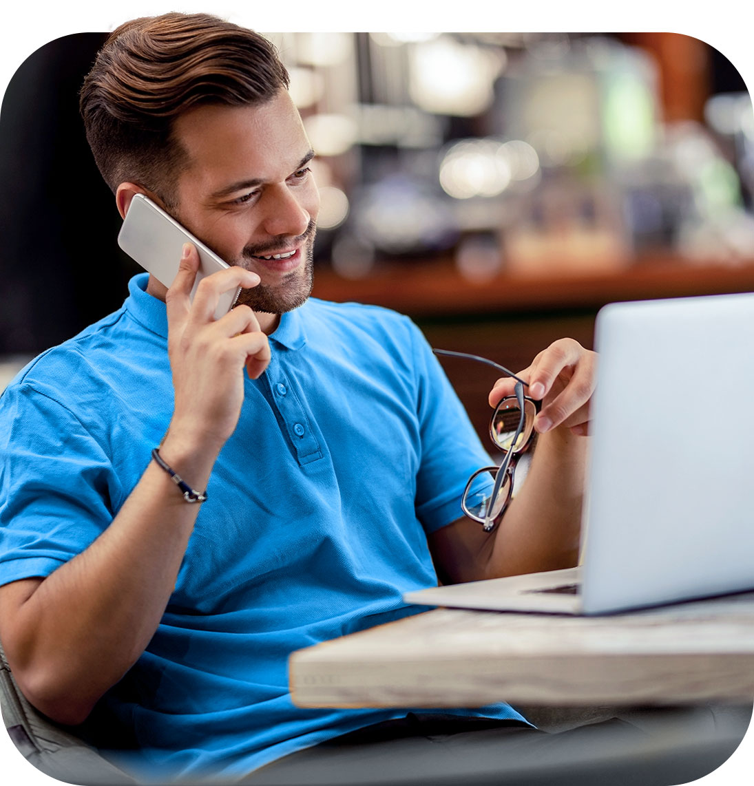 Homem falando ao telefone enquanto trabalha sorrindo